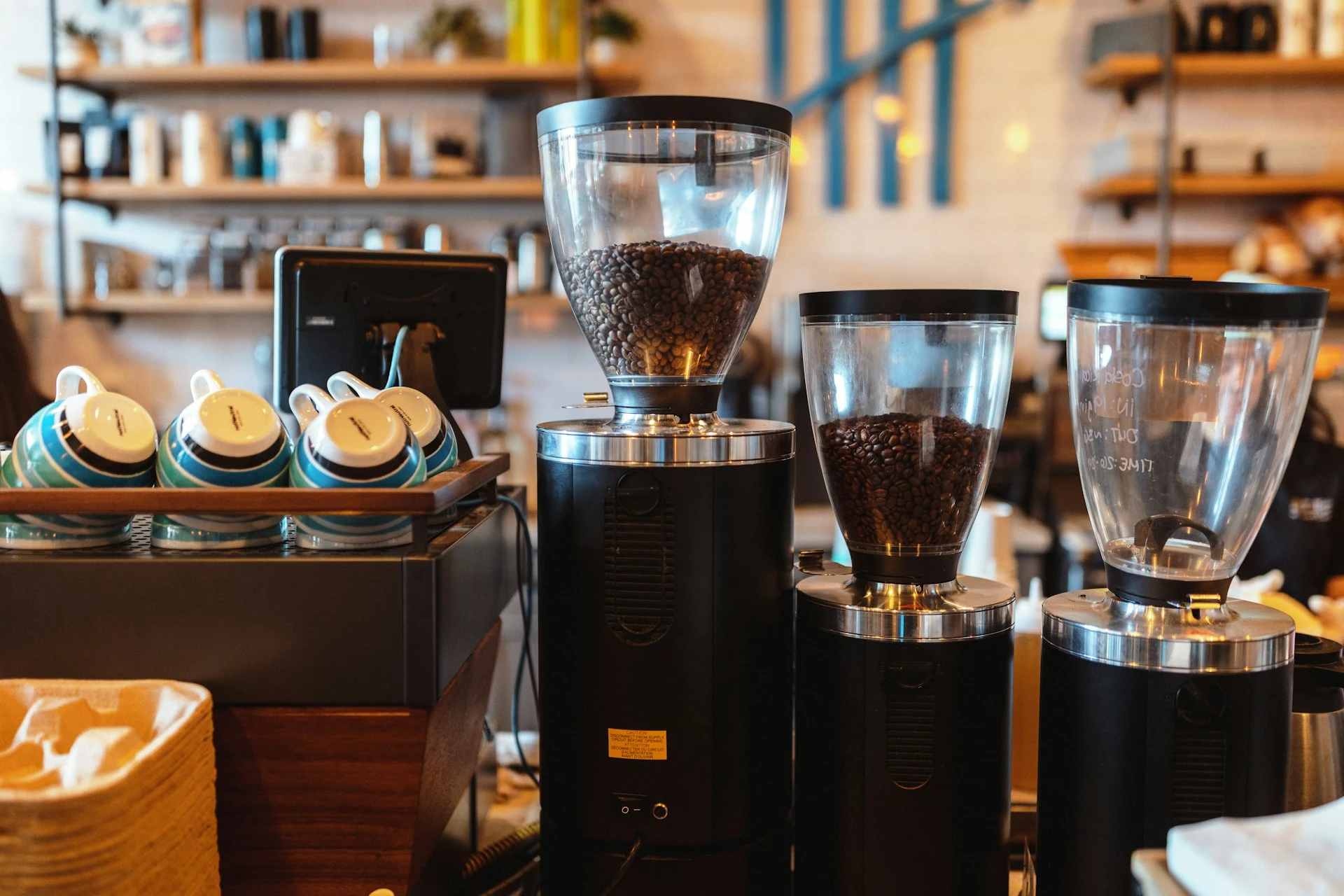 Commercial espresso grinders filled with coffee beans on a café counter