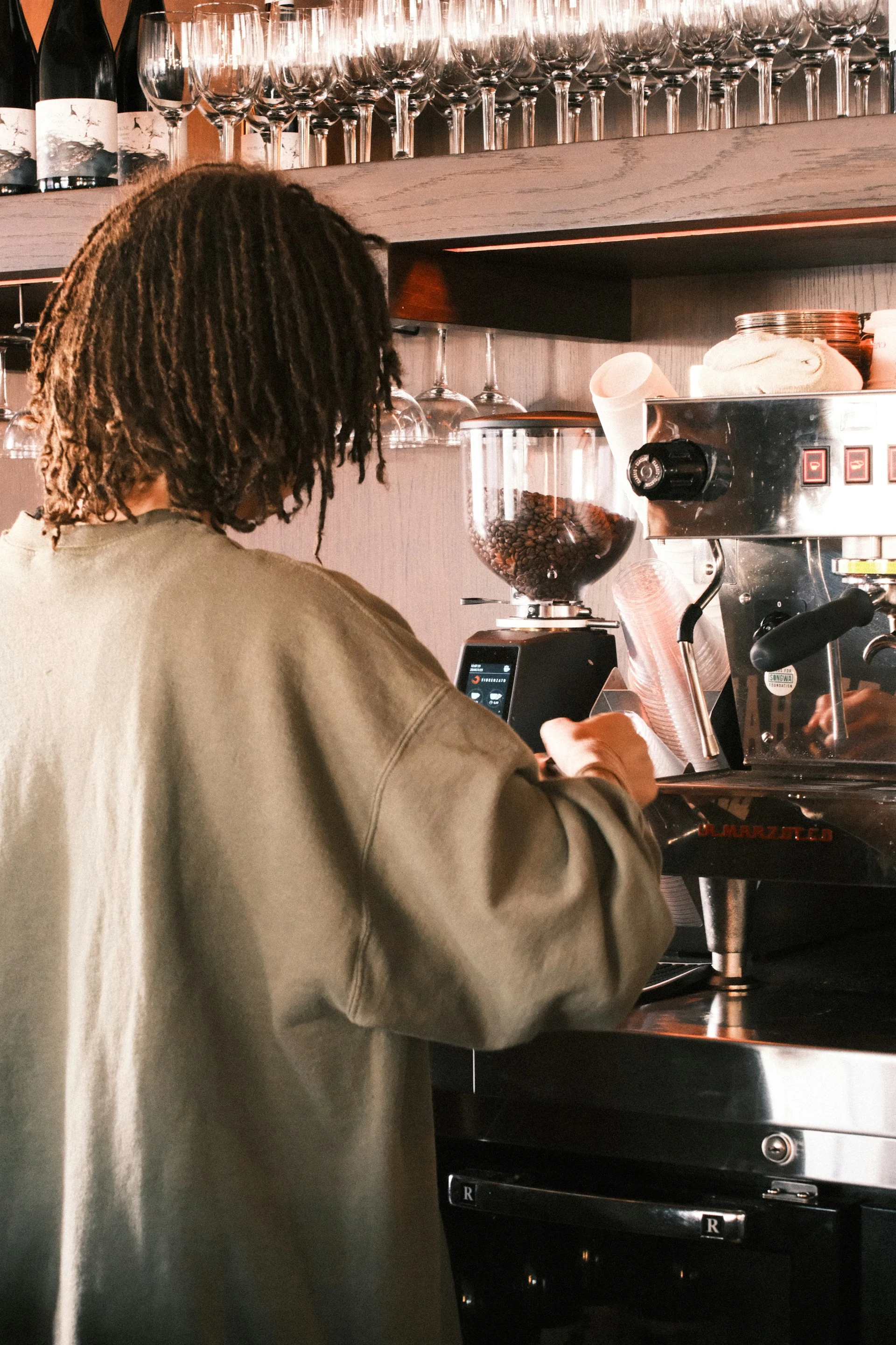 Barista grinding coffee beans for espresso using a professional grinder in a café