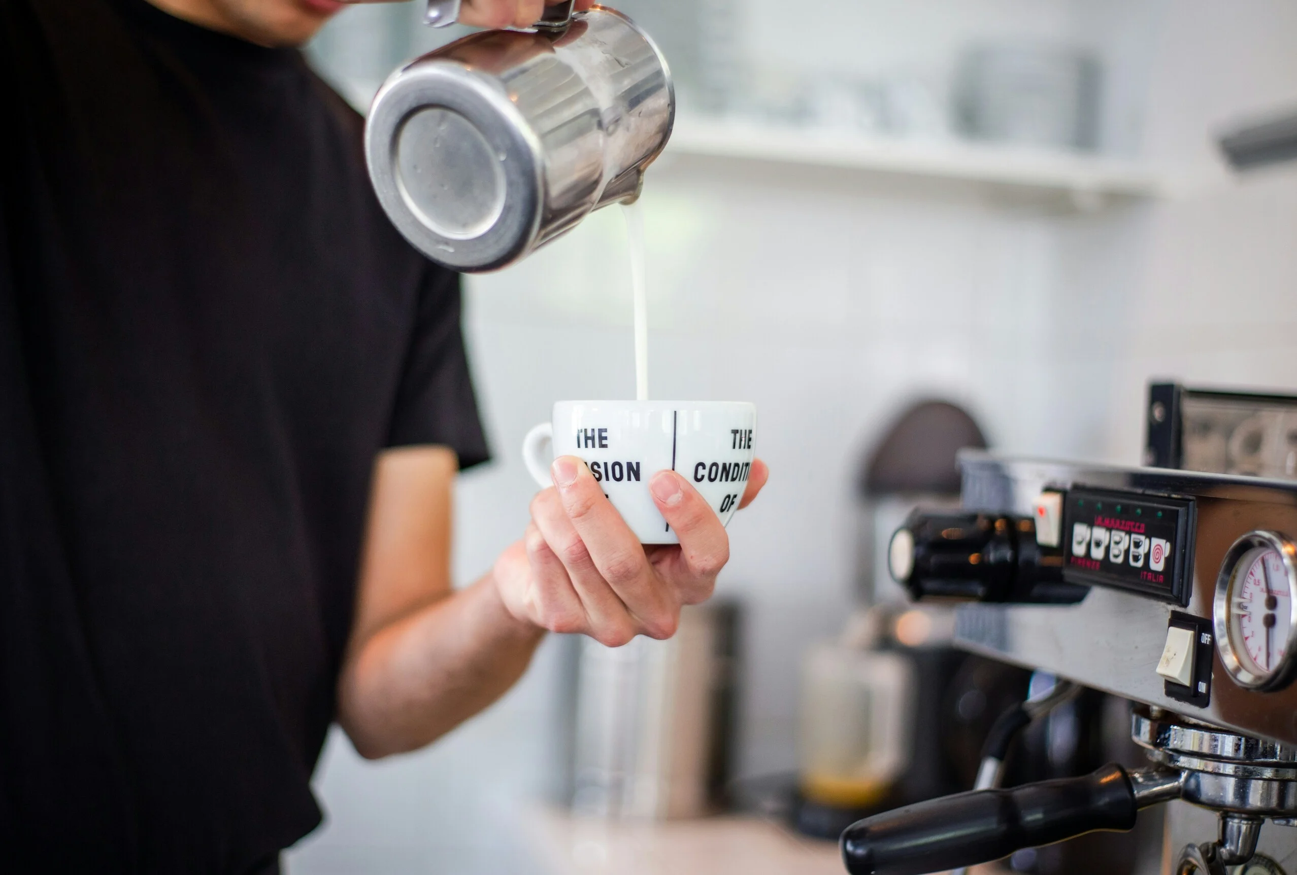 Home barista pouring a simple latte art heart pattern into a cup of coffee